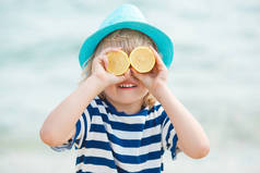 穿条纹 t恤衫的男孩用柠檬遮住眼睛