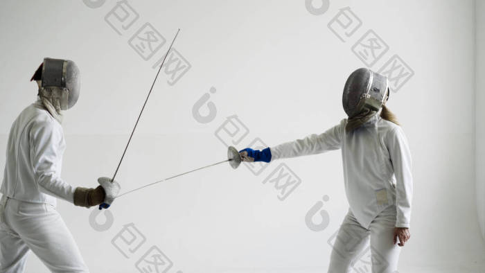 年轻的击剑运动员戴面具和白色击剑服装用灯-包图企业站