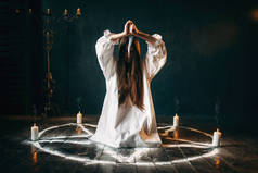 女人用刀坐在五角星圈与蜡烛, 魔术仪式, 神秘主义和驱魔, 超自然的力量
