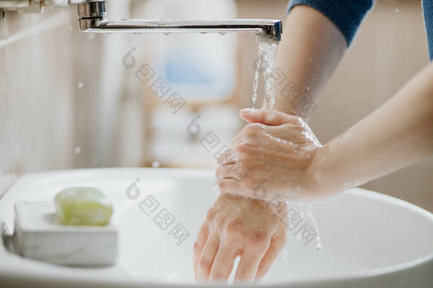 一名妇女在浴室洗手以防止Covid-19病毒感染。建议在大肠病毒大流行期间用肥皂和自来水冲洗.