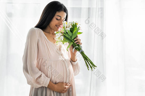 非洲美国孕妇拥抱肚子和气味花束 
