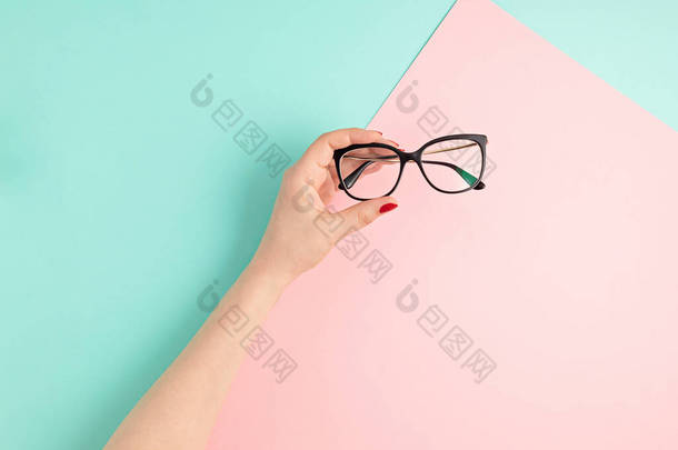 女人举着眼镜。采购产品光学商店,眼镜选择,眼睛测试,视觉检查在眼科医生,时尚配件的概念.俯瞰，平铺