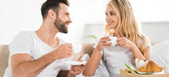 早上在床上吃早餐时用杯子拍摄的美丽情侣全景照片