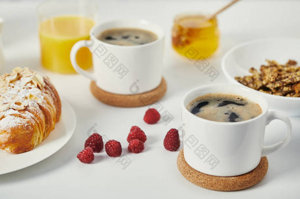 靠近白色表面的咖啡和牛角面包的美味早餐的关闭视图