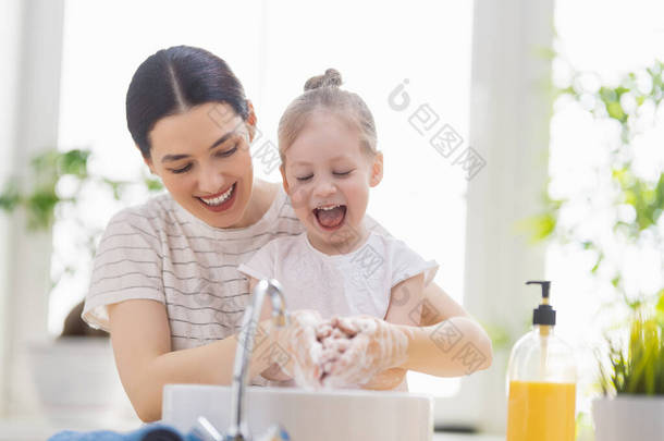 一个可爱的小女孩和她的母亲正在洗手。防止感染和病毒.   