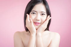 长头发亚洲年轻美丽的女人点手指向上分离在粉红色的背景。自然的化妆、 水疗治疗、 护肤、 美容和整形外科的概念.