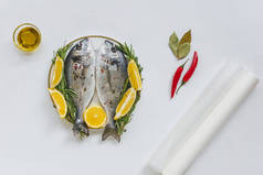 在盘子里看到烤纸、橄榄油和鱼的顶部景色, 这些鱼是用迷迭香和柠檬装饰的