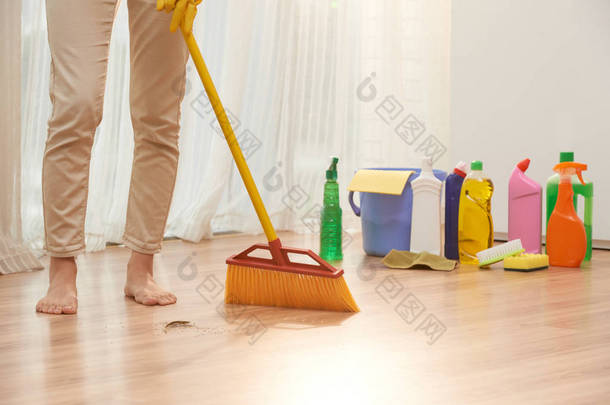 赤脚妇女清扫地板与扫帚, 而裹在清扫