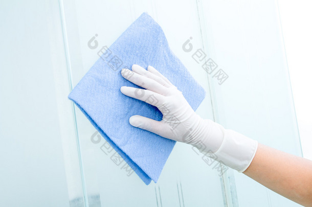 手和手套用蓝色海绵清洗玻璃