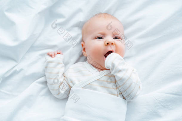 <strong>可爱</strong>的婴儿躺在白色床上<strong>用品</strong>的最高视图 