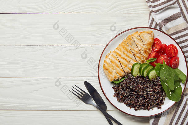 在白色木桌上用餐具和餐巾烤鸡胸肉和<strong>蔬菜</strong>的熟藜麦的顶视图