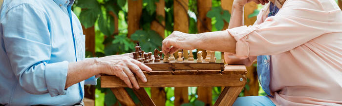 退休夫妇在木桌上下棋的全景镜头 