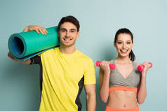 快乐的运动型夫妇，带着健身垫和蓝色哑铃