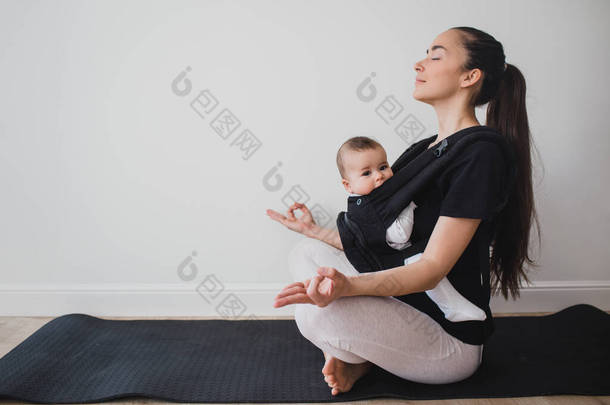 年轻妈妈背着孩子做瑜伽