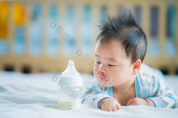 亚洲新生婴儿微笑与电源瓶牛奶