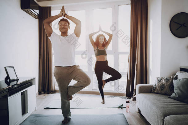 美国黑人夫妇晨练的概念。健身房地毯。一起工作。健康的生活方式。造型运动服。有吸引力的运动员。身体保健。身体移动。家庭健身.