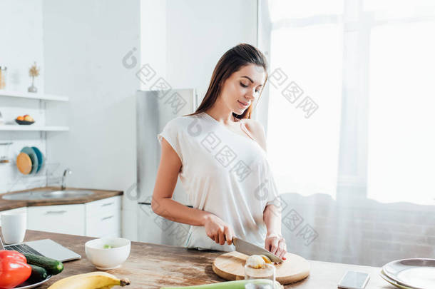 妇女切开橙色与刀在桌在厨房