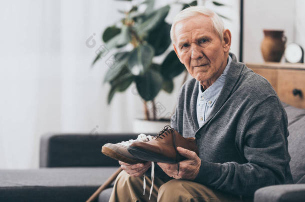 老人拿着经典和现代的鞋在手 