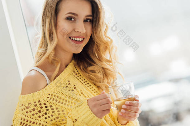 选择焦点美丽的微笑的年轻女子拿着一杯茶, 看着相机