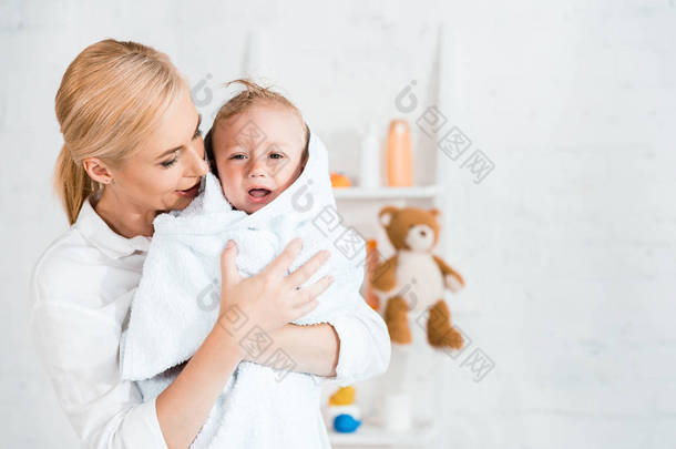 有吸引力的金发母亲抱着在怀里打乱幼儿儿子在浴室 