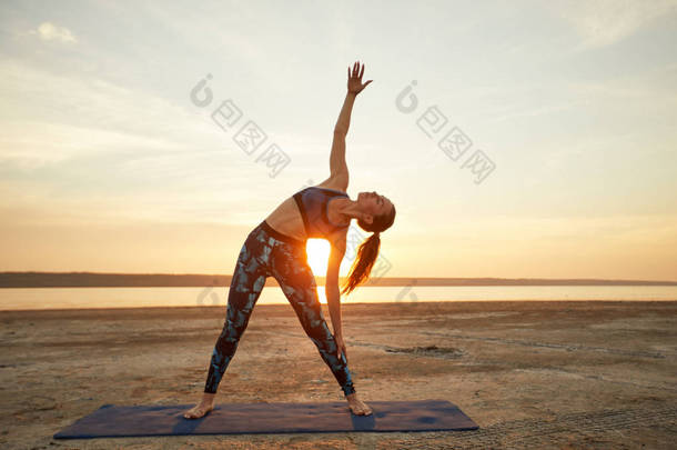 <strong>瑜伽</strong>和健身。年轻女子在沙滩上练习晨练