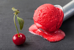 冰淇淋，新鲜樱桃，覆盆子，草莓，蔓越莓，红果冻，勺子。黑石背景