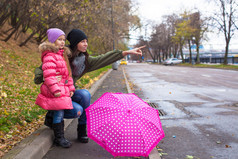 小女孩和她??母亲和伞走在一个下雨天