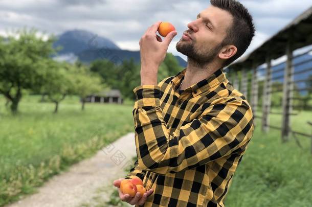 夏天，穿着休闲装的英俊男子一边在山间散步，一边寻开心，拿着杏仁  