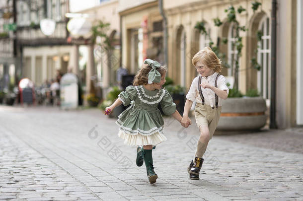 在街<strong>上走来走去</strong>的孩子。男孩和女孩一起跑步。 复古风格的照片。 市中心的铺路工。夏天。德国