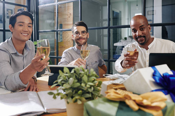 在庆祝新年的时候，积极的多族裔同事坐在会议室的桌旁，喝着起泡的酒