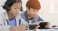 男孩和女孩在家里玩智能手机和平板电脑