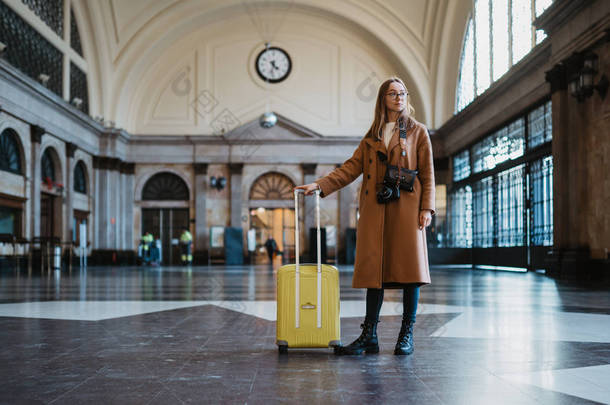 巴塞罗那站台上的女<strong>游客</strong>带着手提箱，用复古相机拍照。 等火车的女旅客在运输铁路享受周末假期。 旅游<strong>火车站</strong>的概念