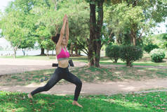 瘦小的女孩在公园的草坪上玩瑜伽，穿着紧身衣放松，亚洲女孩喜欢练习瑜伽