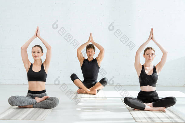 年轻女子和男子<strong>高举</strong>祷告手，在半荷花中练习瑜伽