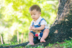 小孩子在树下与大自然的青草嬉戏