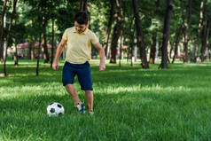 男孩在公园的绿草上踢足球 