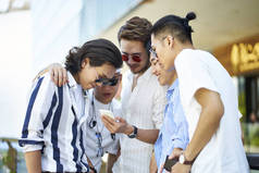 年轻的亚洲成年男子看着手机在一起
