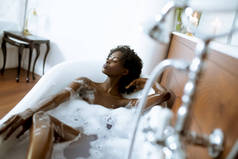 美丽的年轻非洲裔美国妇女沐浴在浴缸里满是泡沫
