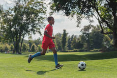 可爱的非洲美国孩子在草地上踢足球 