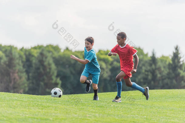 兴奋的多元<strong>文化</strong>的孩子在草地上踢<strong>足球</strong> 