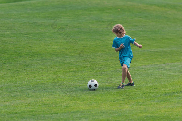 可爱的卷发男孩在绿草地上<strong>踢</strong>足球 