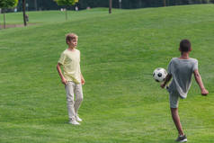 可爱的多元文化的孩子在草地上踢足球 