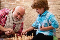 小男孩和他的祖父下棋。象棋。孩子下棋。祖父和孙子在一起的时候下棋和微笑.