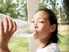 亚洲女孩在户外喝一瓶水.