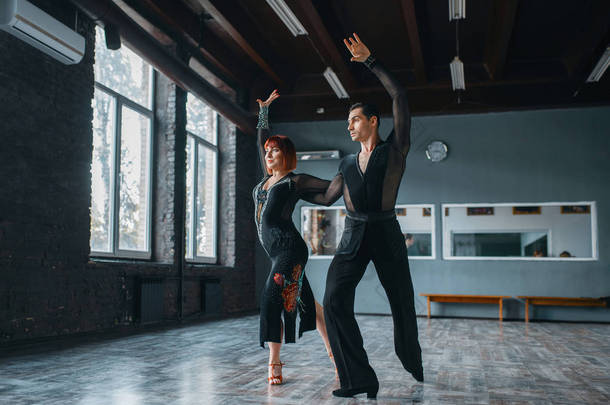 优雅男女在服装上舞蹈训练在课堂上。男女伴侣在工作室的专业对舞