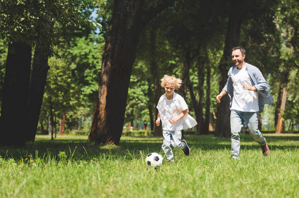 父亲和可爱的儿子<strong>踢</strong>足球与足球在公园与复制空间
