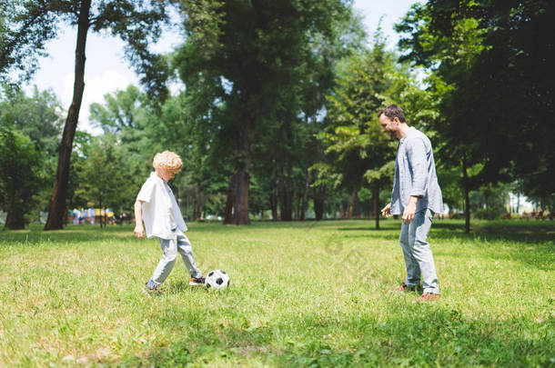 父亲和可爱的儿子一起在公园里<strong>踢</strong>足球
