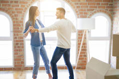 美丽的年轻夫妇搬到一个新的家,跳舞在爱庆祝新的公寓