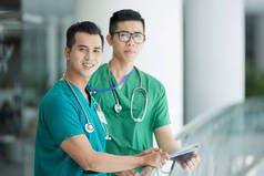 年轻的亚洲全科医生穿着绿色制服微笑着在照相机