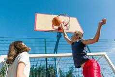 街头篮球比赛与二个球员, 青少年女孩和男孩, 早晨在篮球场